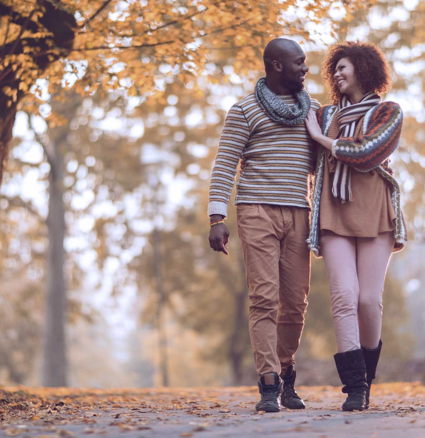 A couple laughing together while walking on an autumn park path