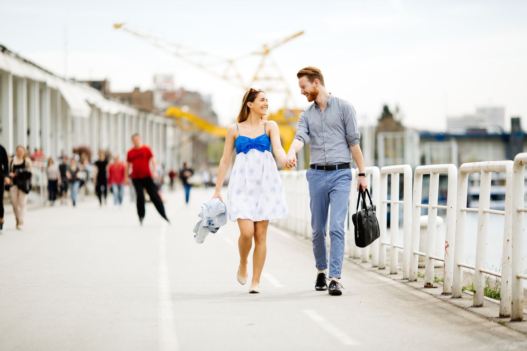 A couple laughing and walking hand in hand outdoors
